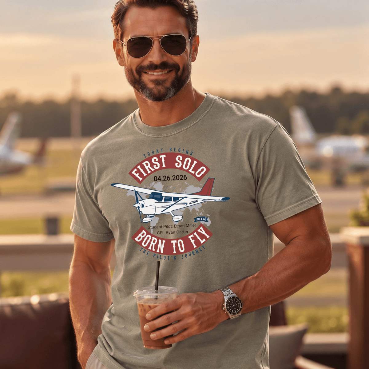 Man wearing a gray-green First Solo T-shirt with an airplane illustration at an airfield