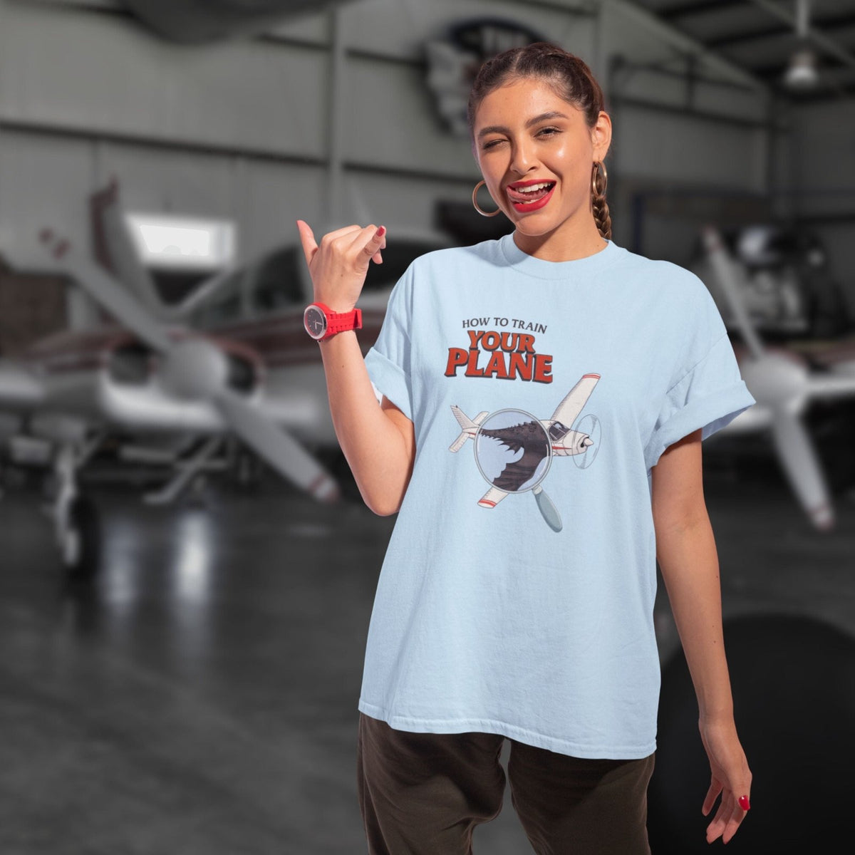 Man wearing a How to Train Your Plane T-shirt in a hangar