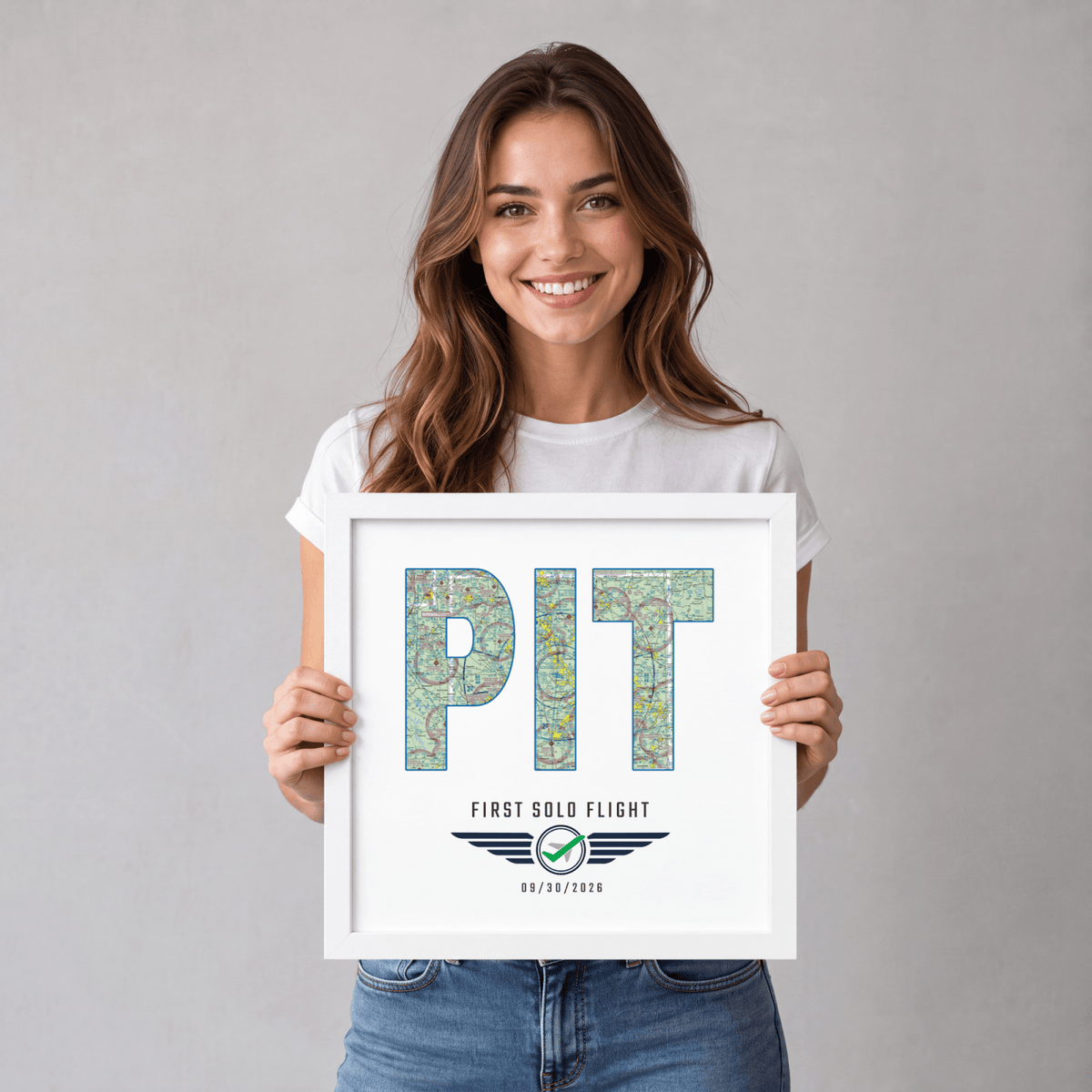 Woman holding a white-framed PIT airport code VFR chart print celebrating a first solo flight