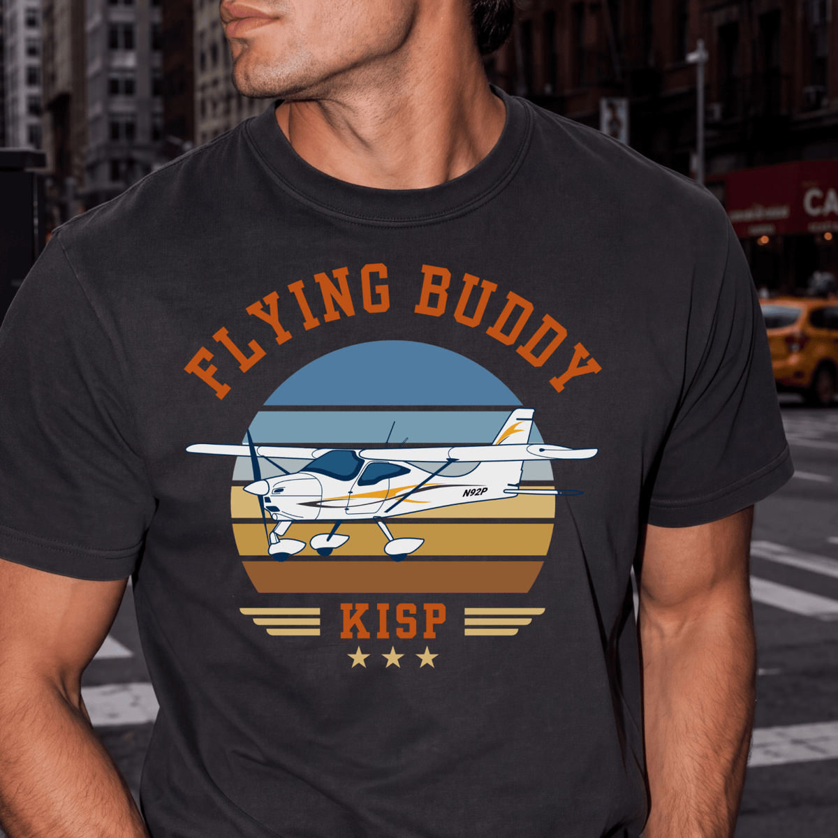 Man wearing a black Flying Buddy T-shirt with a high-wing airplane and KISP airport code