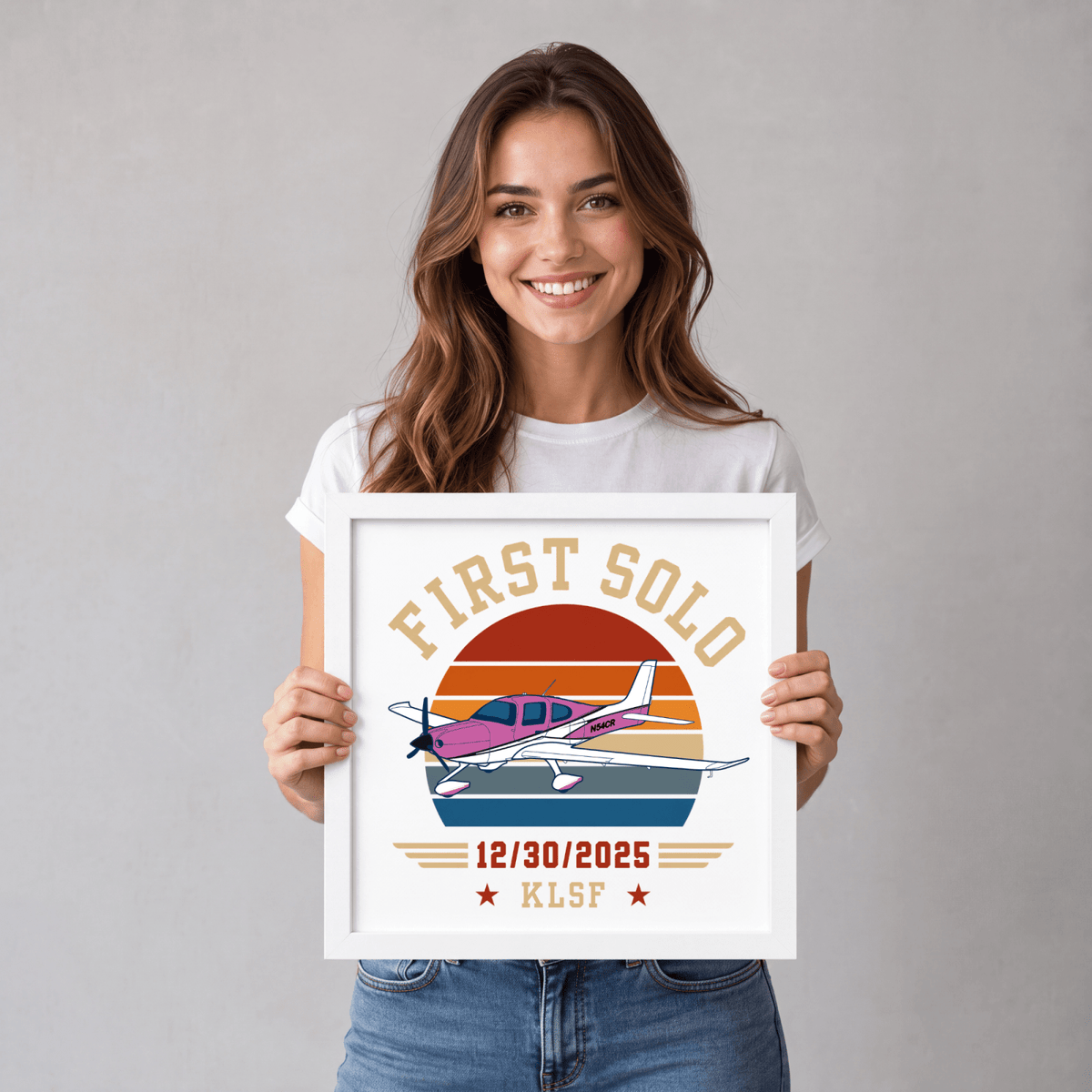 Woman holding a white-framed first solo print with a colorful aircraft