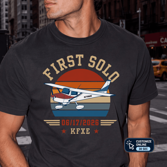 Man wearing a black First Solo T-shirt with a high-wing airplane, retro sunset, personalized date, and airport code