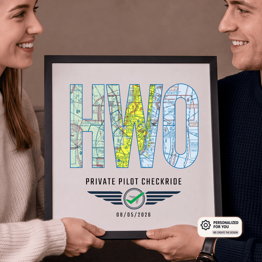 Couple holding a black-framed HWO airport code print personalized with a private pilot checkride date
