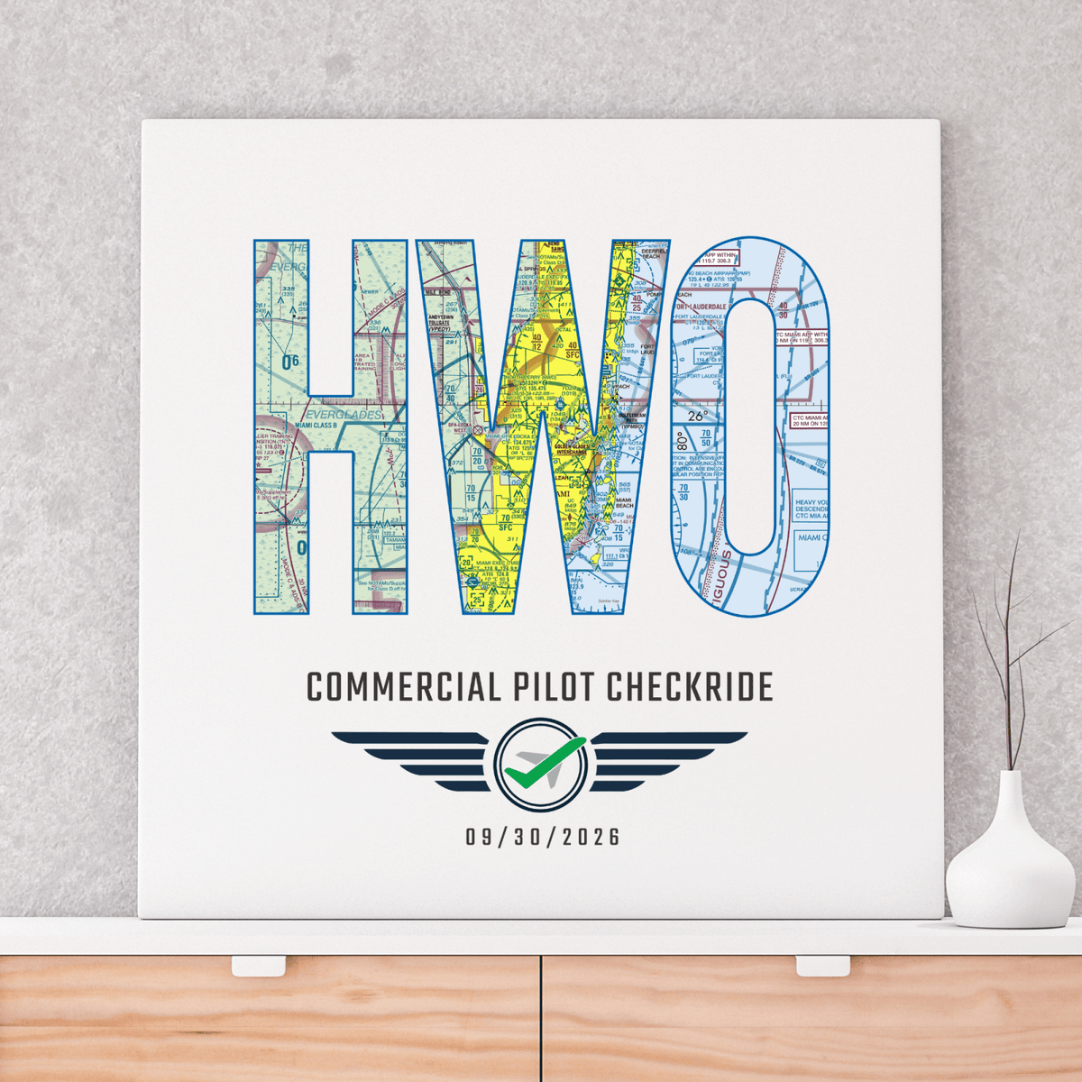 Unframed HWO airport code commercial pilot checkride print displayed above a wooden cabinet